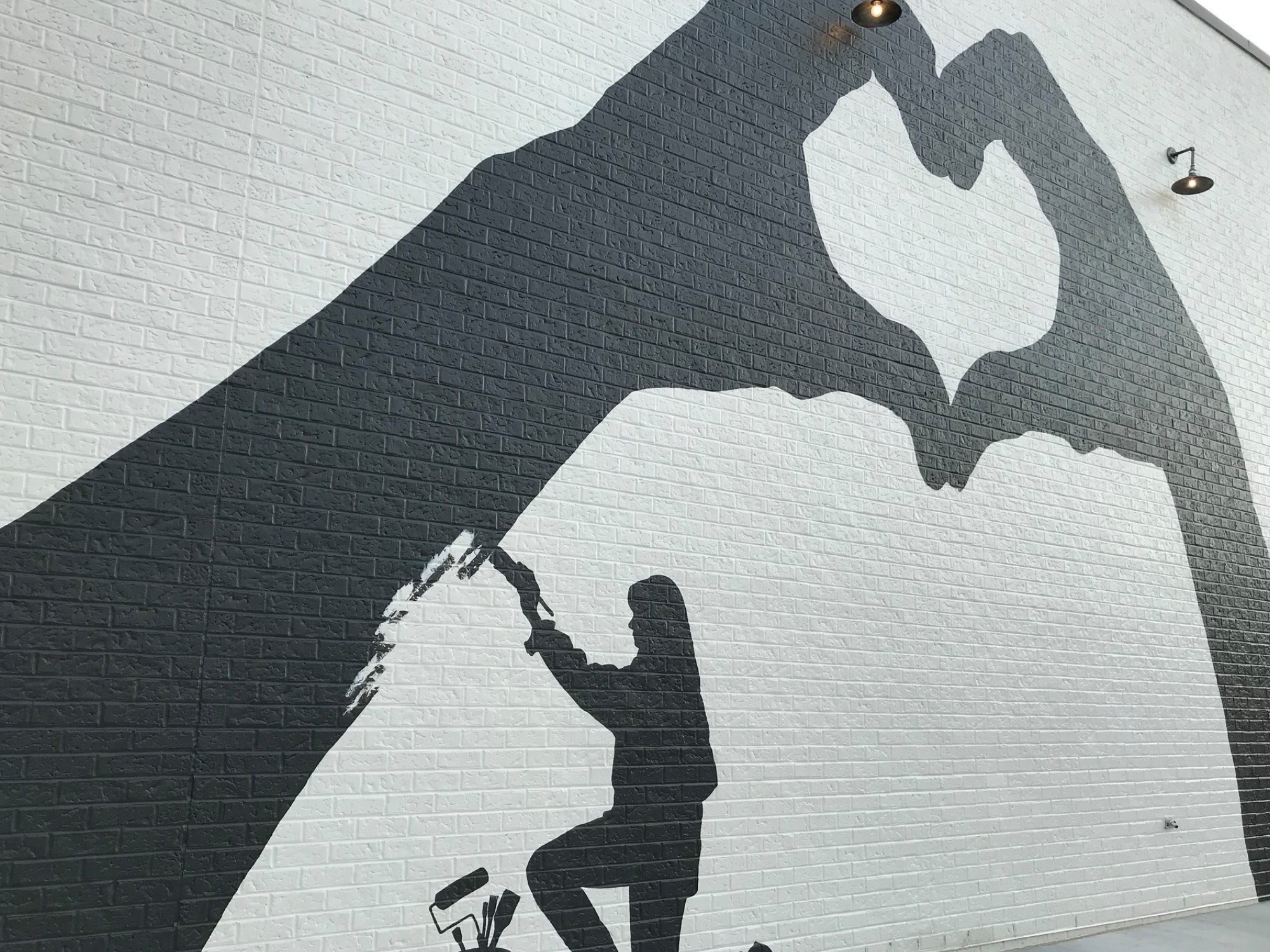 Mural of hand shadows making heart on white brick wall